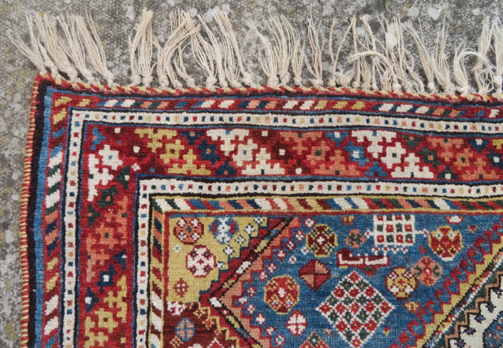 An antique hand-knotted Luri tribal rug featuring central diamond medallions on an indigo blue field framed by geometric red borders. View XI