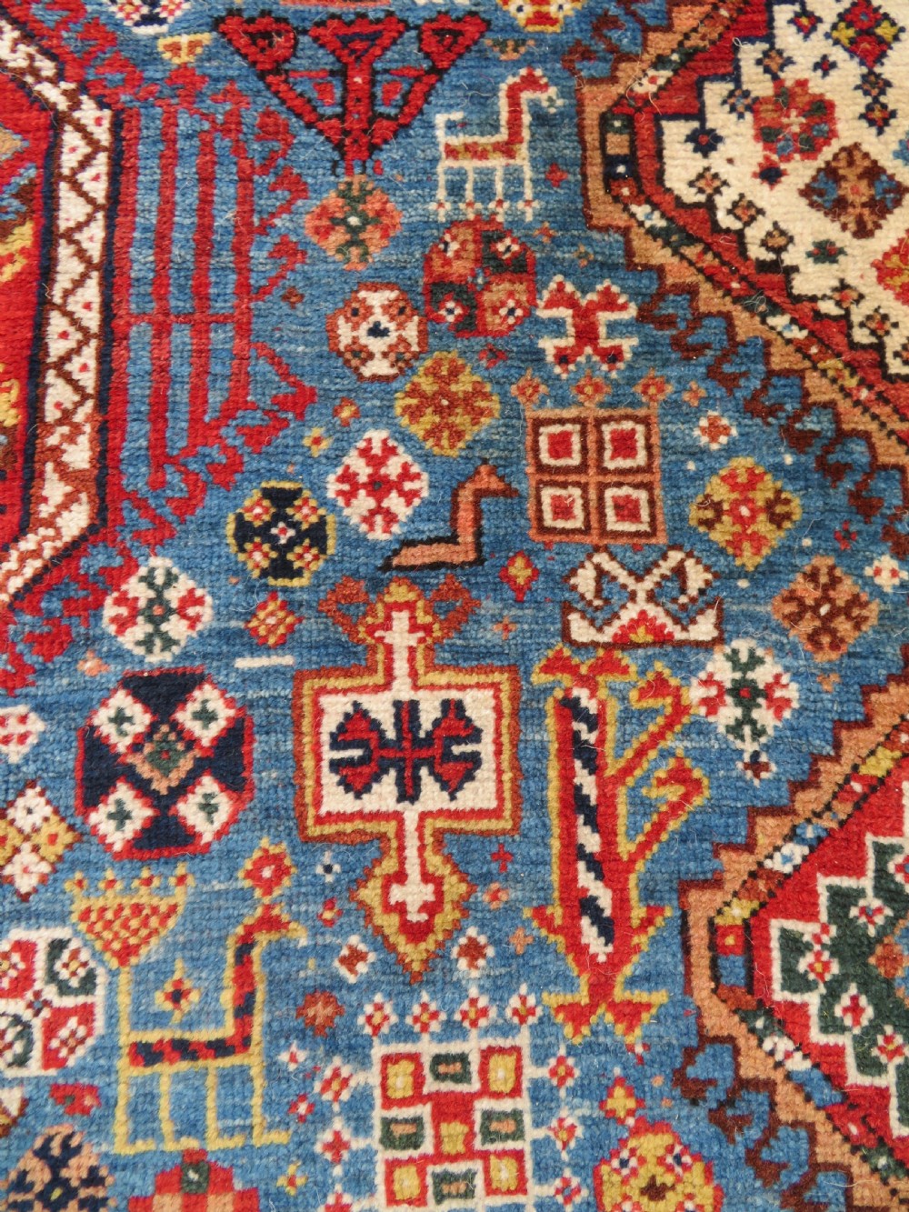 An antique hand-knotted Luri tribal rug featuring central diamond medallions on an indigo blue field framed by geometric red borders. View XIII