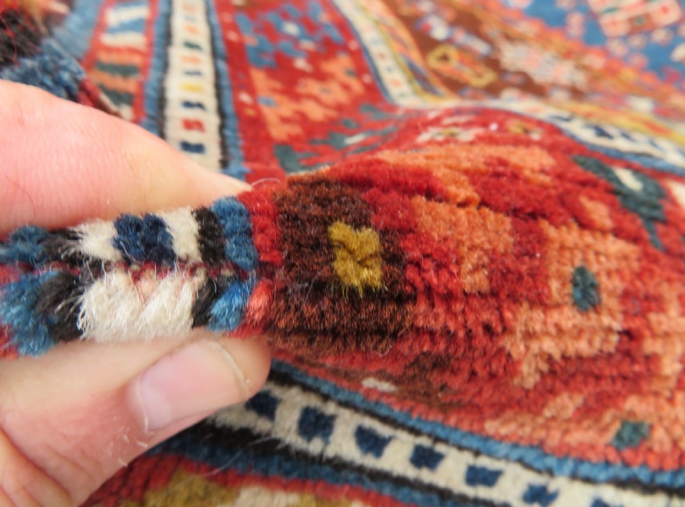 An antique hand-knotted Luri tribal rug featuring central diamond medallions on an indigo blue field framed by geometric red borders. View XV