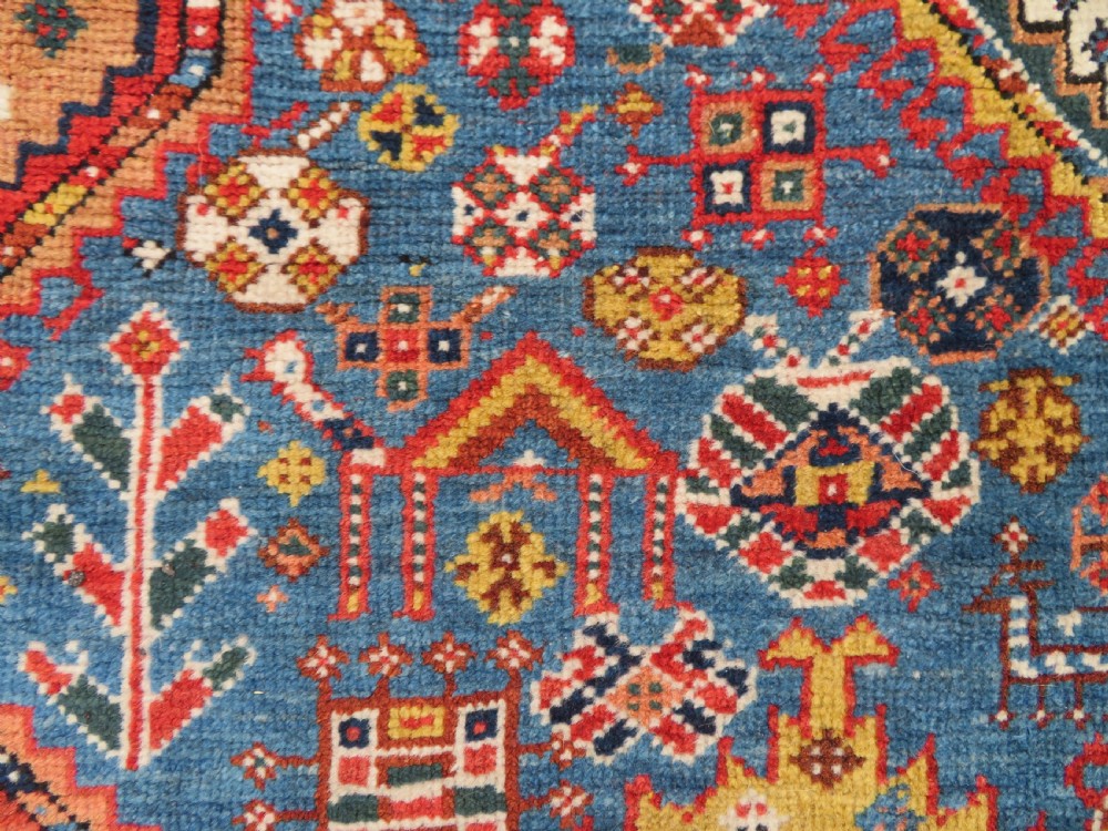 An antique hand-knotted Luri tribal rug featuring central diamond medallions on an indigo blue field framed by geometric red borders. View XVI
