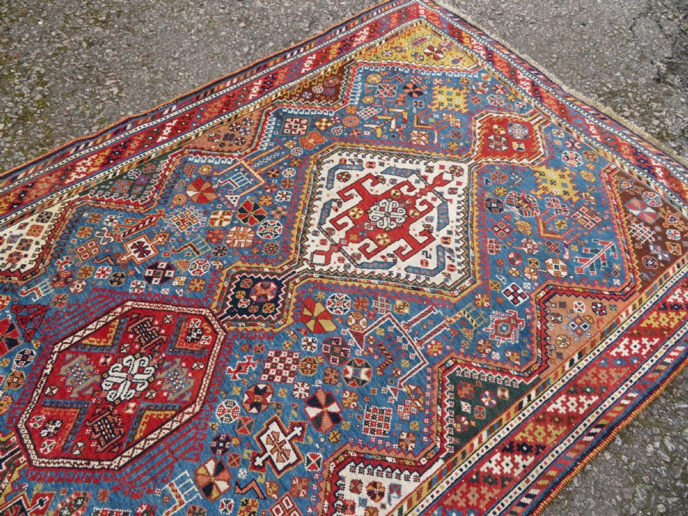 An antique hand-knotted Luri tribal rug featuring central diamond medallions on an indigo blue field framed by geometric red borders. View XXI