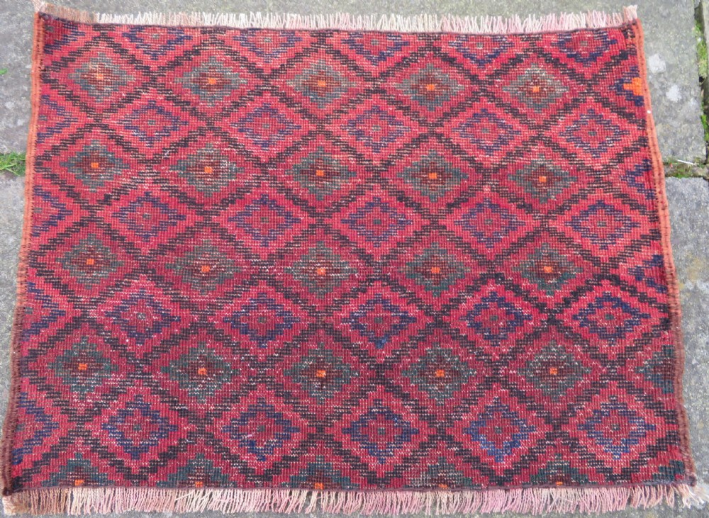 An antique hand-woven Luri saddle bag face featuring a repeating geometric diamond lattice pattern in shades of red, dark blue, cyan, and orange with fringed edges. View II