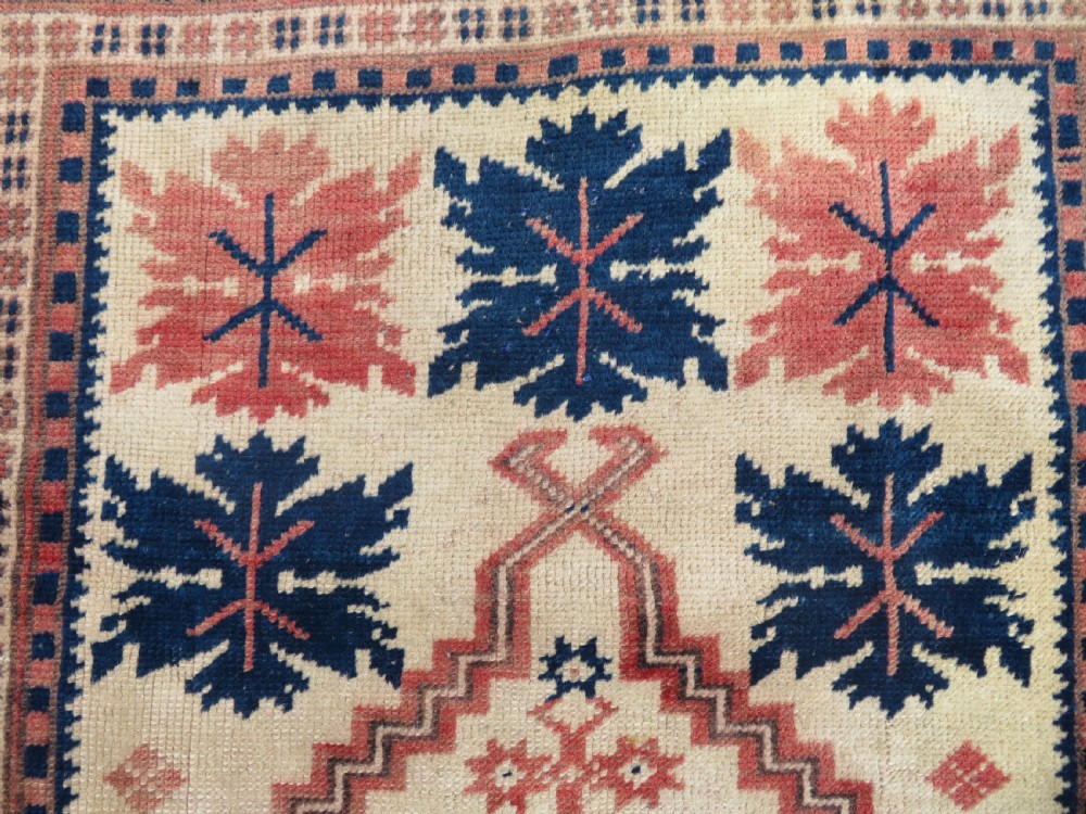 A hand-knotted wool Anatolian Bergama prayer rug featuring an ivory central field with a geometric arched mihrab design framed by terracotta and navy blue geometric borders. View V
