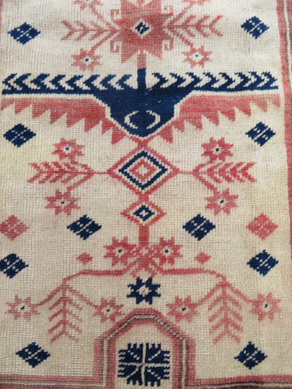 A hand-knotted wool Anatolian Bergama prayer rug featuring an ivory central field with a geometric arched mihrab design framed by terracotta and navy blue geometric borders. View VI