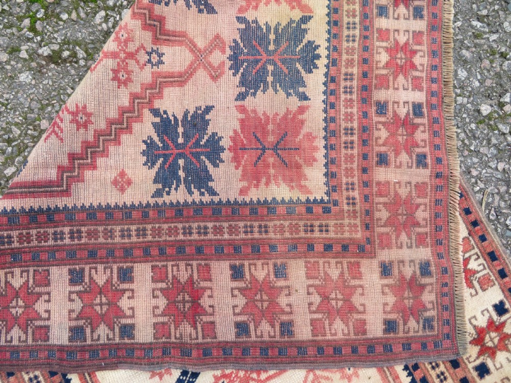 A hand-knotted wool Anatolian Bergama prayer rug featuring an ivory central field with a geometric arched mihrab design framed by terracotta and navy blue geometric borders. View X