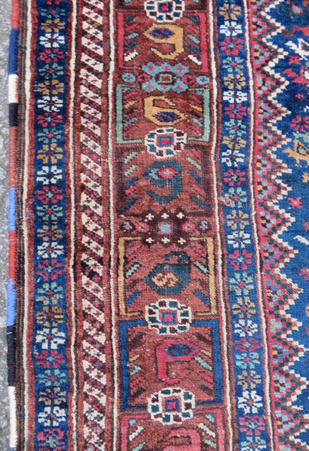 An antique Persian Khamseh rug featuring three central diamond medallions surrounded by small animal motifs and a geometric border in indigo blue and terracotta red tones. View X