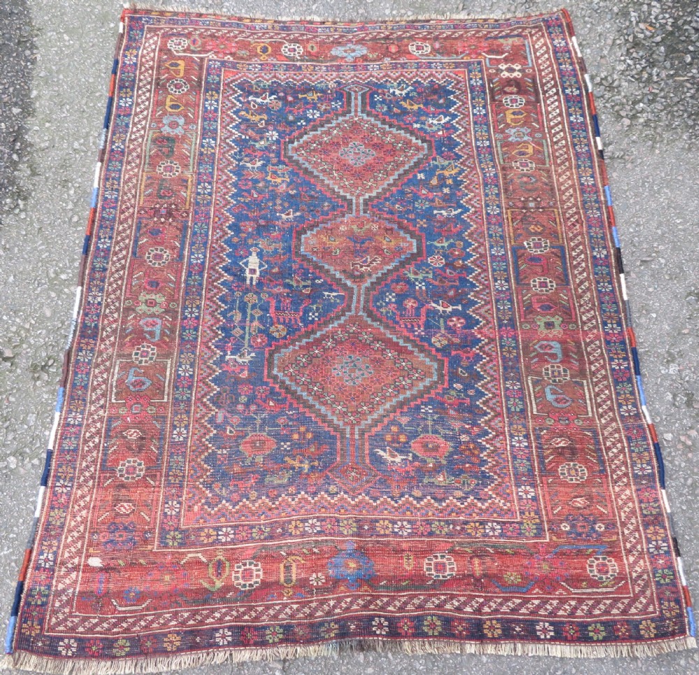 An antique Persian Khamseh rug featuring three central diamond medallions surrounded by small animal motifs and a geometric border in indigo blue and terracotta red tones. View XI