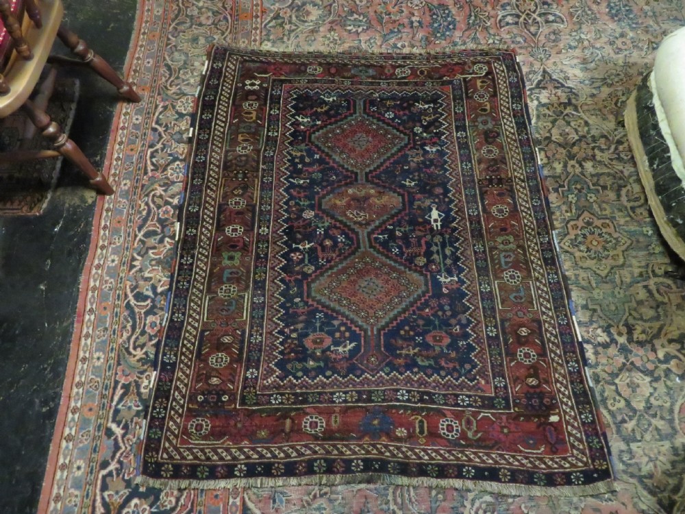 An antique Persian Khamseh rug featuring three central diamond medallions surrounded by small animal motifs and a geometric border in indigo blue and terracotta red tones. View XIV