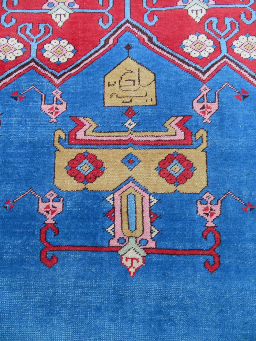 A mid-19th-century hand-knotted Turkish Ladik prayer rug featuring a blue central niche on a red ground with inverted tulip motifs and a patterned yellow border. View III