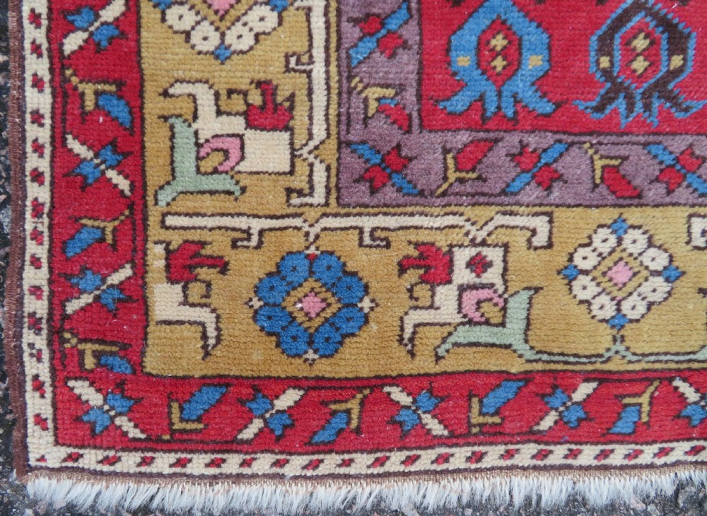 A mid-19th-century hand-knotted Turkish Ladik prayer rug featuring a blue central niche on a red ground with inverted tulip motifs and a patterned yellow border. View IV