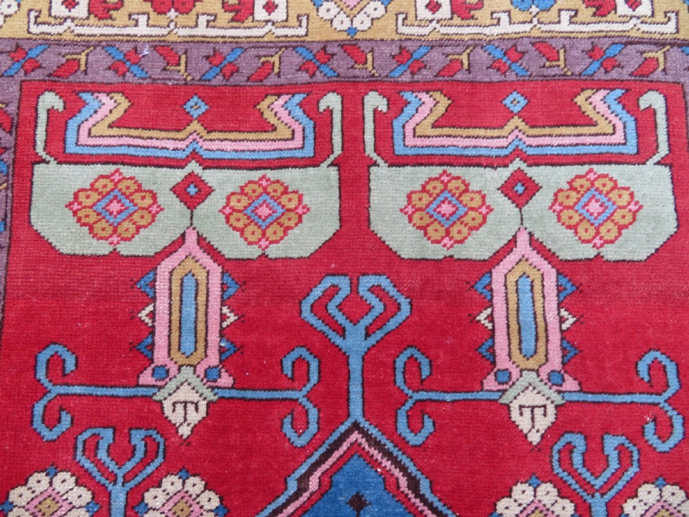 A mid-19th-century hand-knotted Turkish Ladik prayer rug featuring a blue central niche on a red ground with inverted tulip motifs and a patterned yellow border. View V