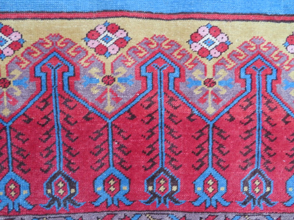 A mid-19th-century hand-knotted Turkish Ladik prayer rug featuring a blue central niche on a red ground with inverted tulip motifs and a patterned yellow border. View IX