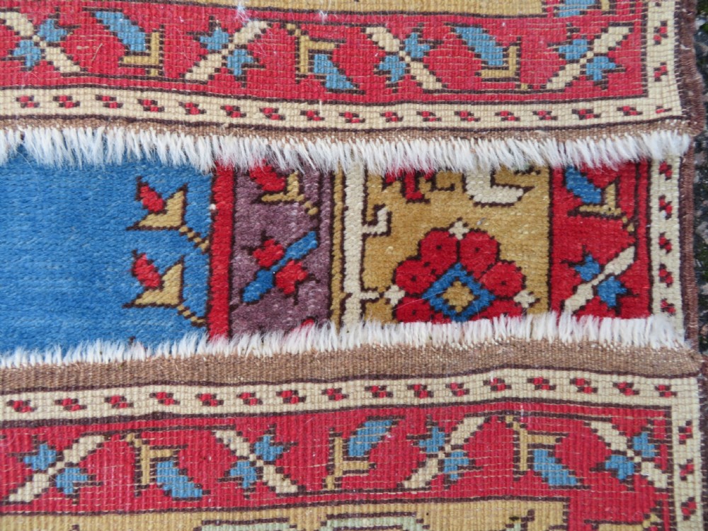 A mid-19th-century hand-knotted Turkish Ladik prayer rug featuring a blue central niche on a red ground with inverted tulip motifs and a patterned yellow border. View XI