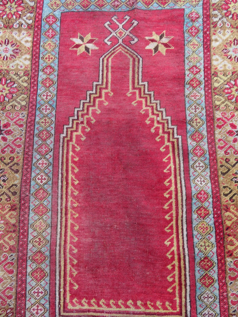 A mid-19th-century hand-knotted Turkish Mudjur prayer rug with a red central mihrab niche framed by geometric floral patterned borders. View IV