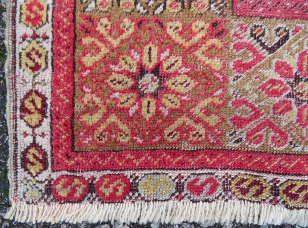 A mid-19th-century hand-knotted Turkish Mudjur prayer rug with a red central mihrab niche framed by geometric floral patterned borders. View V