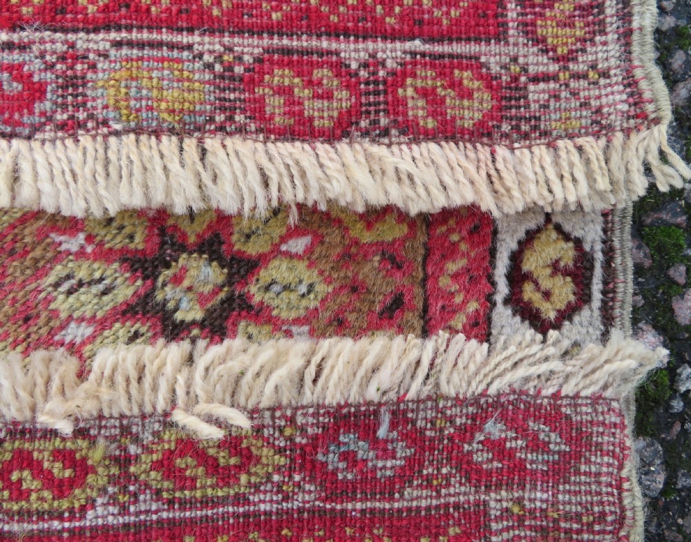 A mid-19th-century hand-knotted Turkish Mudjur prayer rug with a red central mihrab niche framed by geometric floral patterned borders. View X