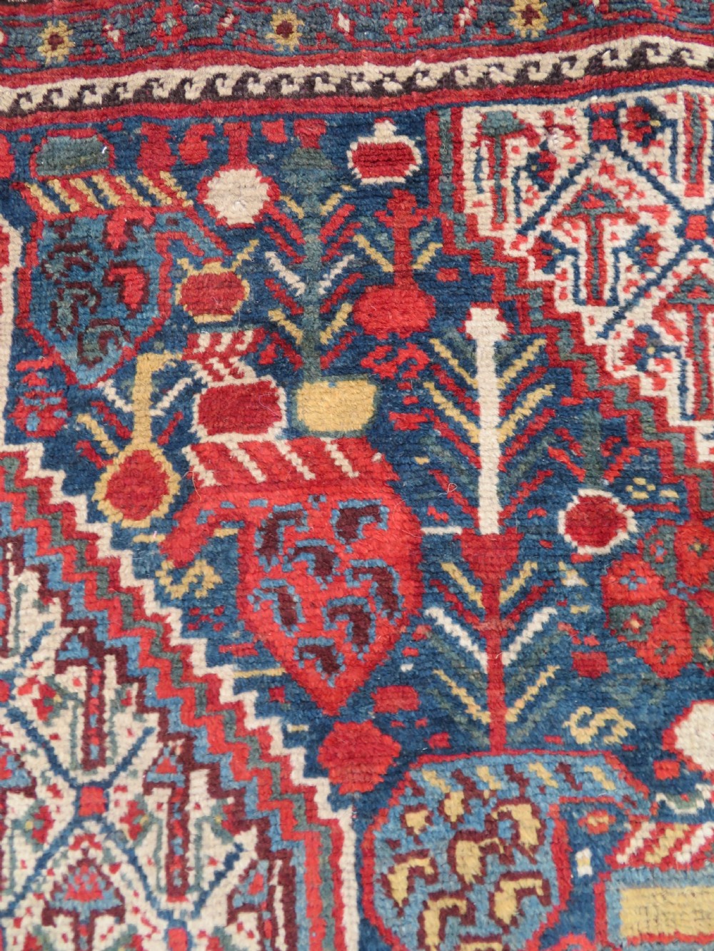 An antique Khamseh Basseri hand-knotted wool rug featuring geometric diamond medallions in red, blue, and ivory tones. View VIII
