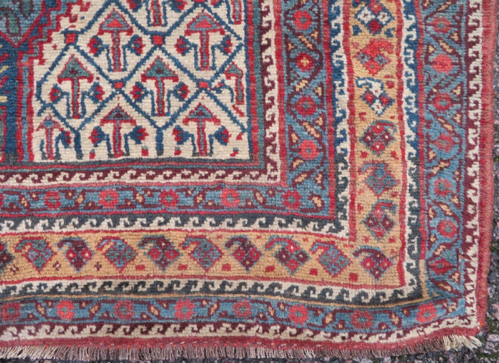An antique Khamseh Basseri hand-knotted wool rug featuring geometric diamond medallions in red, blue, and ivory tones. View XIV