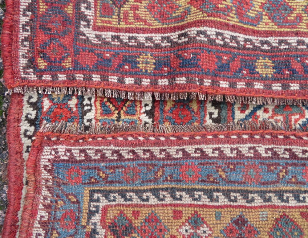 An antique Khamseh Basseri hand-knotted wool rug featuring geometric diamond medallions in red, blue, and ivory tones. View XVIII