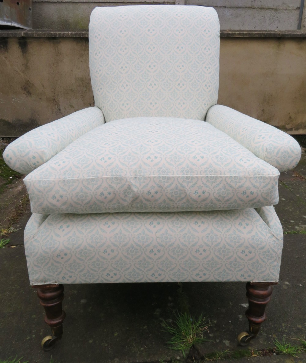 A low-seated Victorian easy chair upholstered in pale blue and cream patterned fabric with turned wooden front legs and brass castors. View VIII