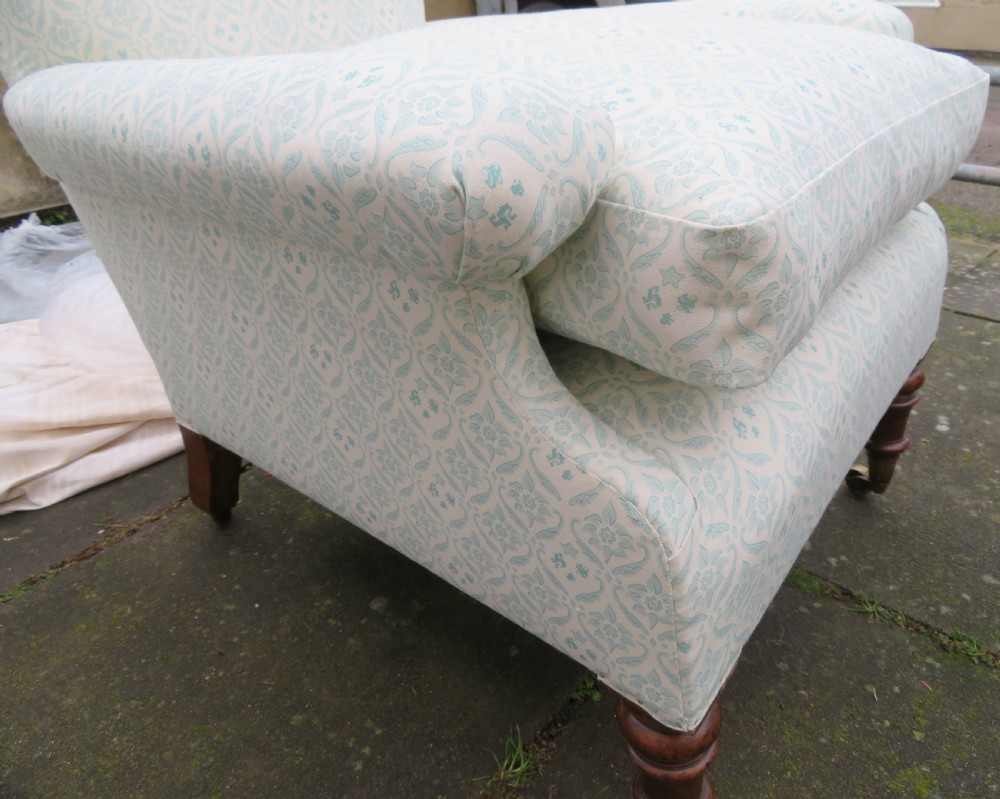 A low-seated Victorian easy chair upholstered in pale blue and cream patterned fabric with turned wooden front legs and brass castors. View IX