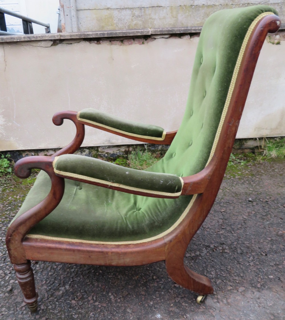 A Victorian mahogany elbow armchair upholstered in button-backed green velvet with scrolled arms and brass castors. View II