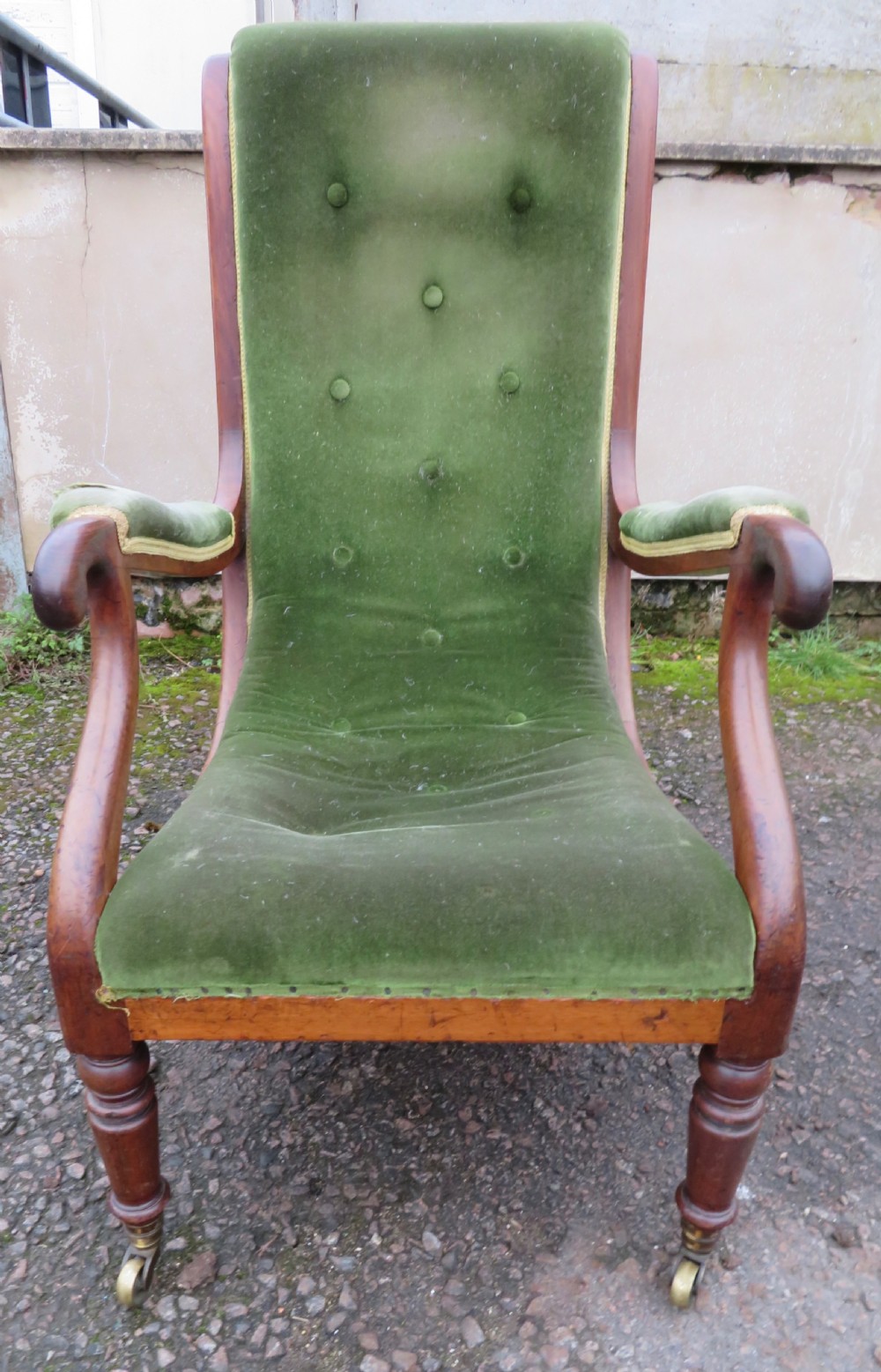 A Victorian mahogany elbow armchair upholstered in button-backed green velvet with scrolled arms and brass castors. View III