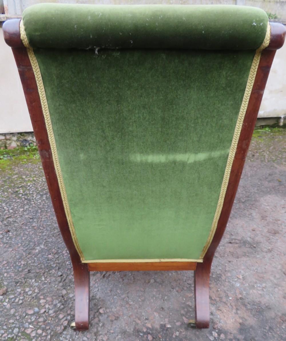 A Victorian mahogany elbow armchair upholstered in button-backed green velvet with scrolled arms and brass castors. View V