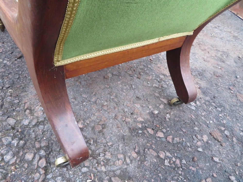 A Victorian mahogany elbow armchair upholstered in button-backed green velvet with scrolled arms and brass castors. View VI