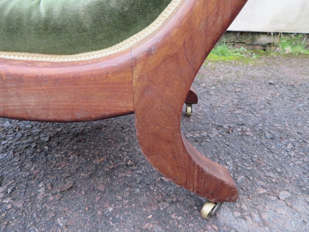 A Victorian mahogany elbow armchair upholstered in button-backed green velvet with scrolled arms and brass castors. View VII