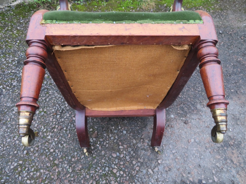 A Victorian mahogany elbow armchair upholstered in button-backed green velvet with scrolled arms and brass castors. View XX