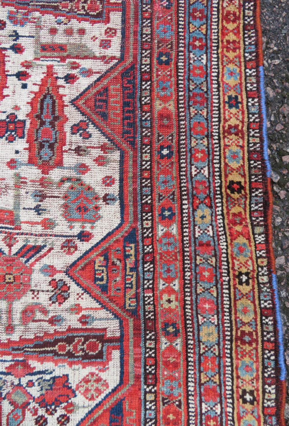 An antique hand-knotted Khamseh tribal rug featuring two diamond medallions on an ivory field filled with bird and geometric motifs, surrounded by a red patterned border. View V