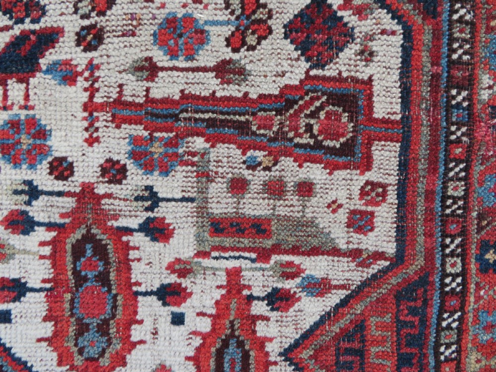 An antique hand-knotted Khamseh tribal rug featuring two diamond medallions on an ivory field filled with bird and geometric motifs, surrounded by a red patterned border. View VIII