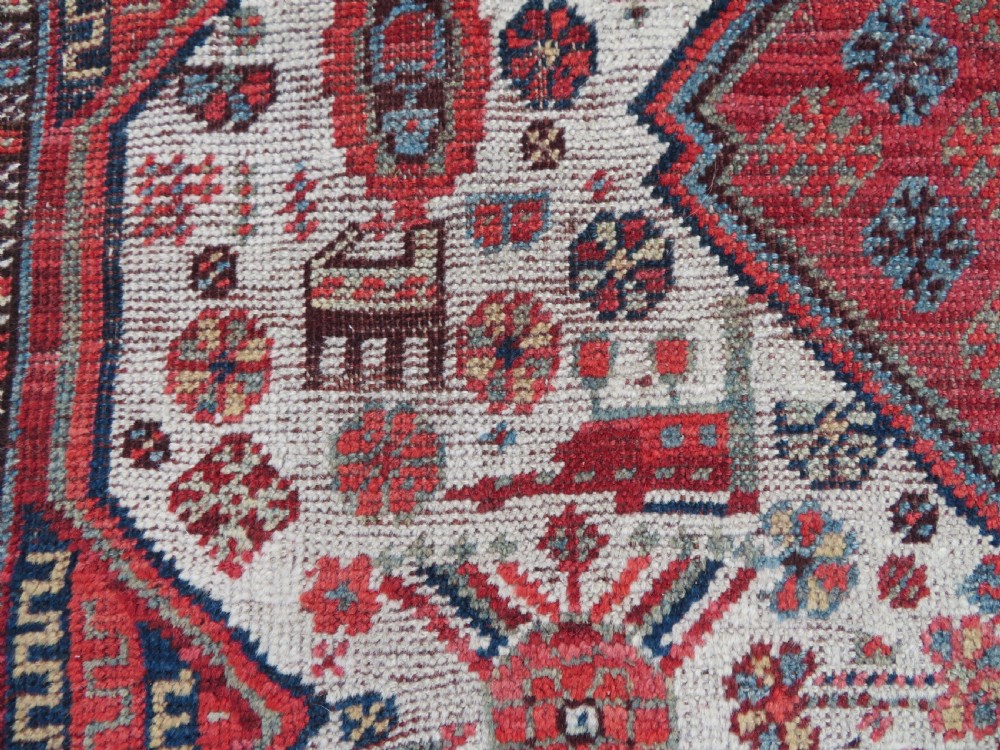 An antique hand-knotted Khamseh tribal rug featuring two diamond medallions on an ivory field filled with bird and geometric motifs, surrounded by a red patterned border. View IX