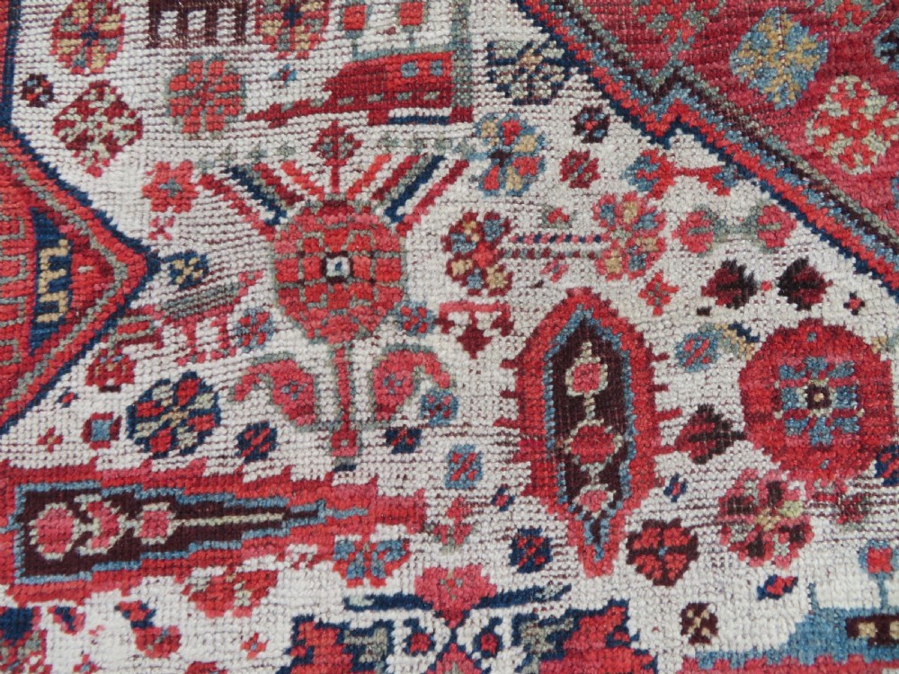 An antique hand-knotted Khamseh tribal rug featuring two diamond medallions on an ivory field filled with bird and geometric motifs, surrounded by a red patterned border. View XI