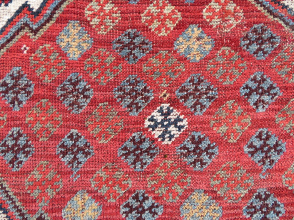 An antique hand-knotted Khamseh tribal rug featuring two diamond medallions on an ivory field filled with bird and geometric motifs, surrounded by a red patterned border. View XII