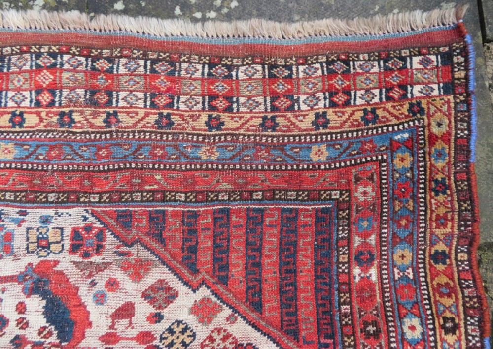 An antique hand-knotted Khamseh tribal rug featuring two diamond medallions on an ivory field filled with bird and geometric motifs, surrounded by a red patterned border. View XIII