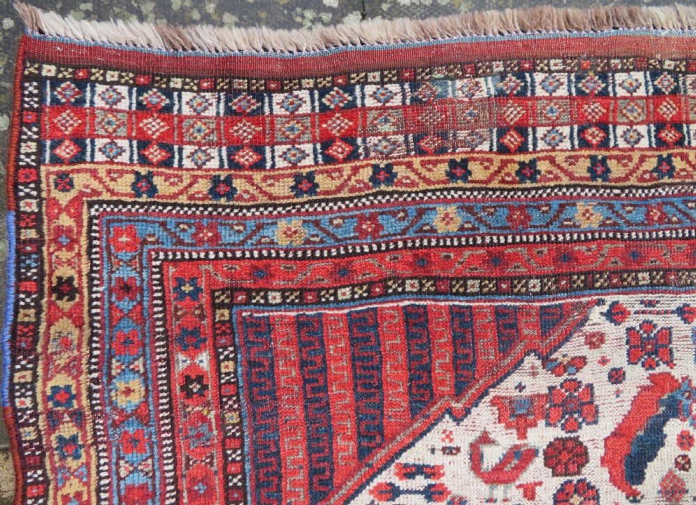 An antique hand-knotted Khamseh tribal rug featuring two diamond medallions on an ivory field filled with bird and geometric motifs, surrounded by a red patterned border. View XV