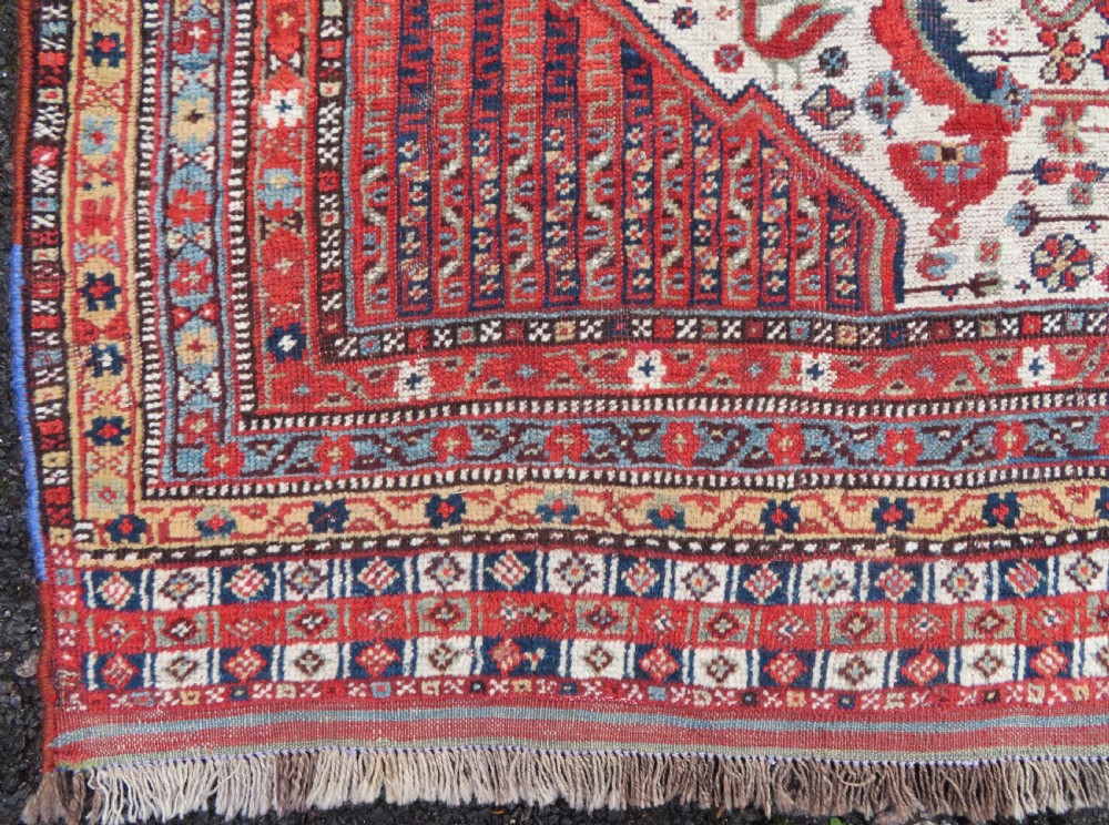 An antique hand-knotted Khamseh tribal rug featuring two diamond medallions on an ivory field filled with bird and geometric motifs, surrounded by a red patterned border. View XVI