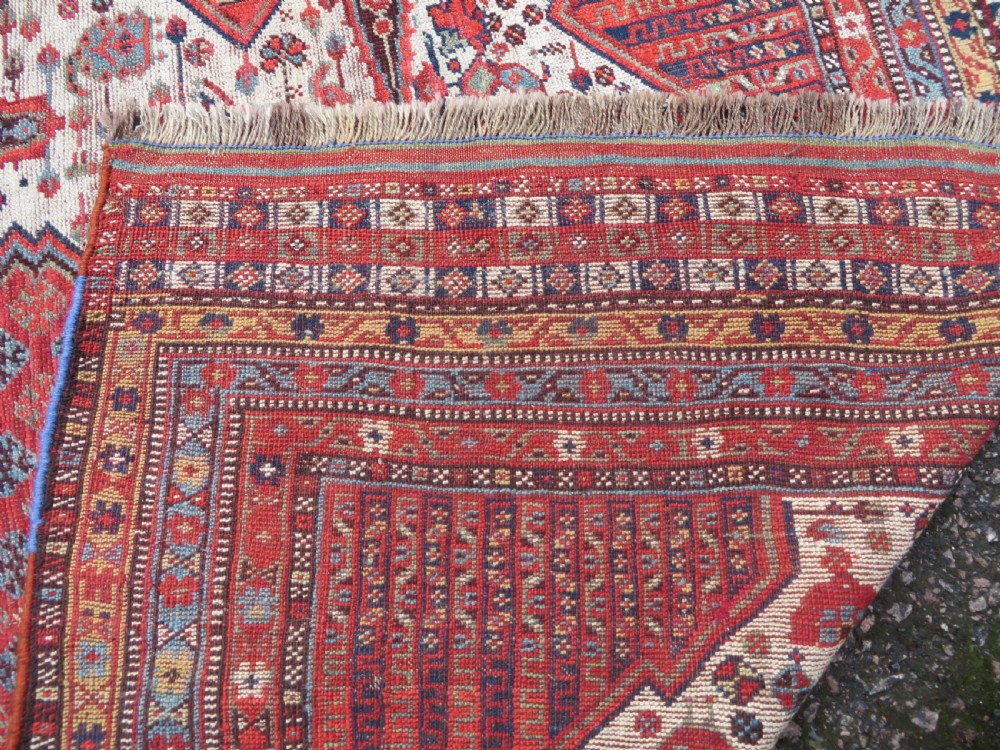 An antique hand-knotted Khamseh tribal rug featuring two diamond medallions on an ivory field filled with bird and geometric motifs, surrounded by a red patterned border. View XVII