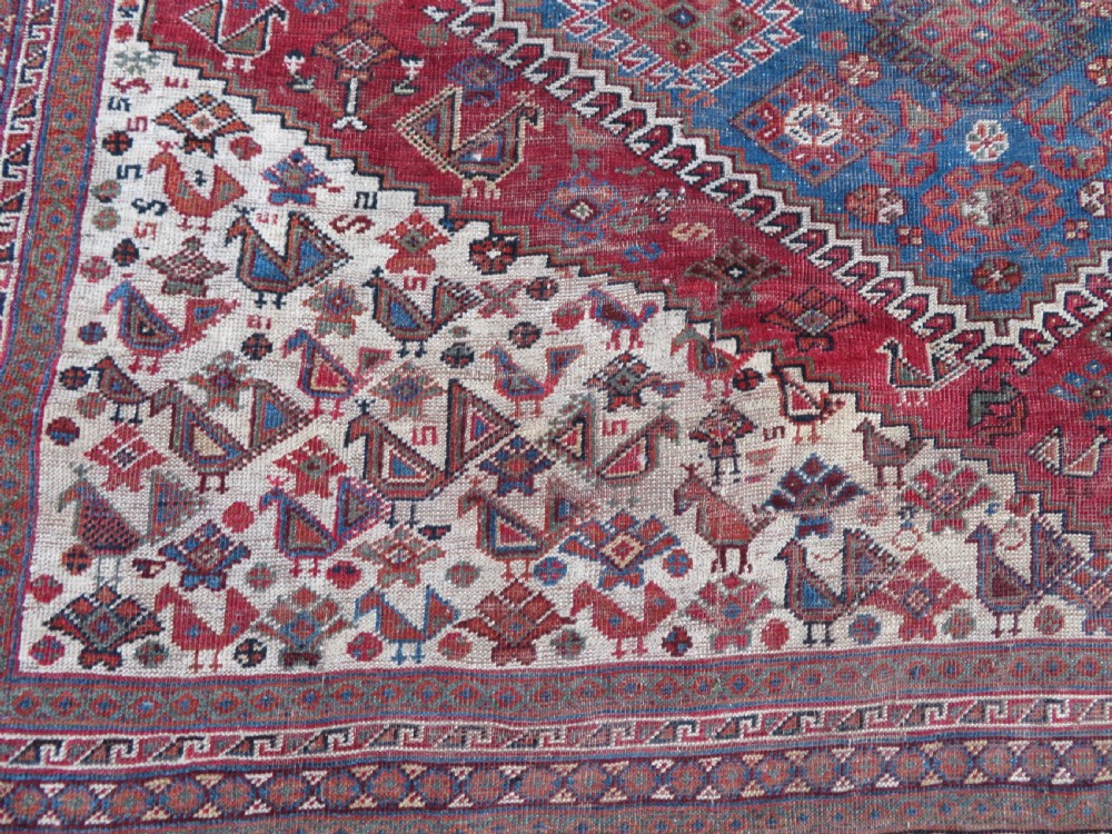 An antique hand-knotted Khamseh tribal kelleh carpet with a dark red field, geometric diamond medallions, and small bird motifs. View VII