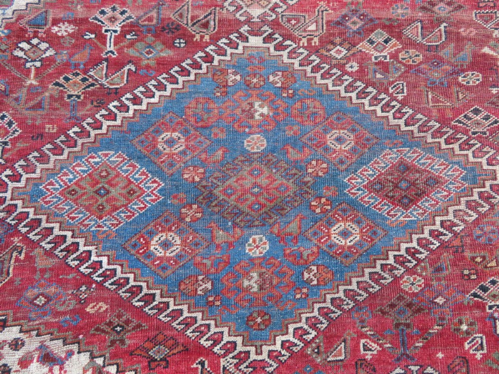 An antique hand-knotted Khamseh tribal kelleh carpet with a dark red field, geometric diamond medallions, and small bird motifs. View VIII