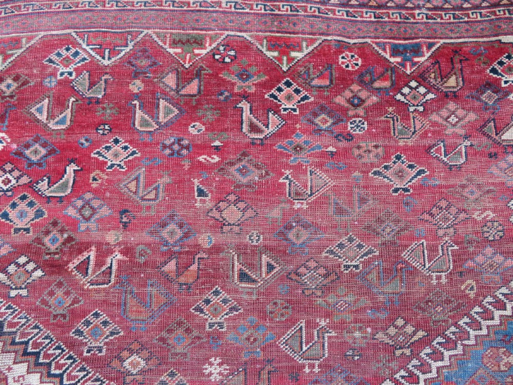 An antique hand-knotted Khamseh tribal kelleh carpet with a dark red field, geometric diamond medallions, and small bird motifs. View XI