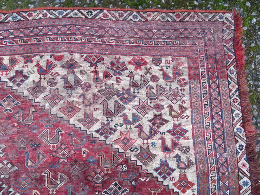 An antique hand-knotted Khamseh tribal kelleh carpet with a dark red field, geometric diamond medallions, and small bird motifs. View XIV