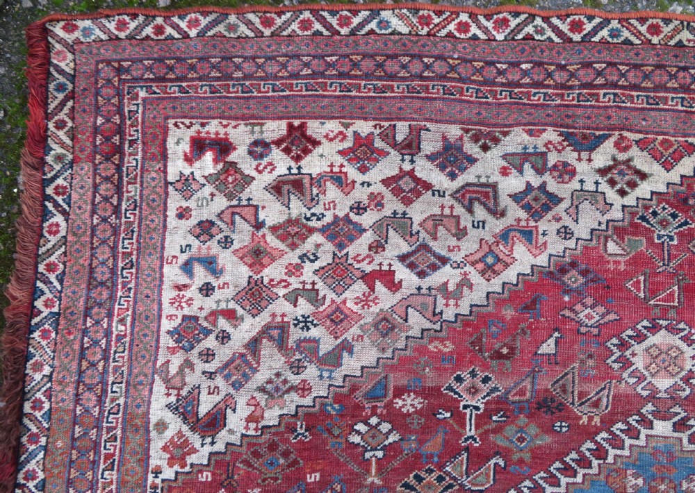 An antique hand-knotted Khamseh tribal kelleh carpet with a dark red field, geometric diamond medallions, and small bird motifs. View XVI