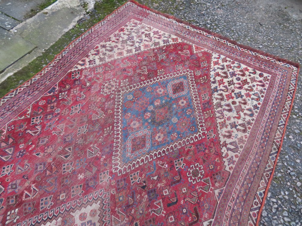 An antique hand-knotted Khamseh tribal kelleh carpet with a dark red field, geometric diamond medallions, and small bird motifs. View XVIII