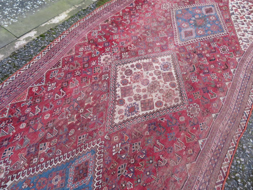 An antique hand-knotted Khamseh tribal kelleh carpet with a dark red field, geometric diamond medallions, and small bird motifs. View XIX