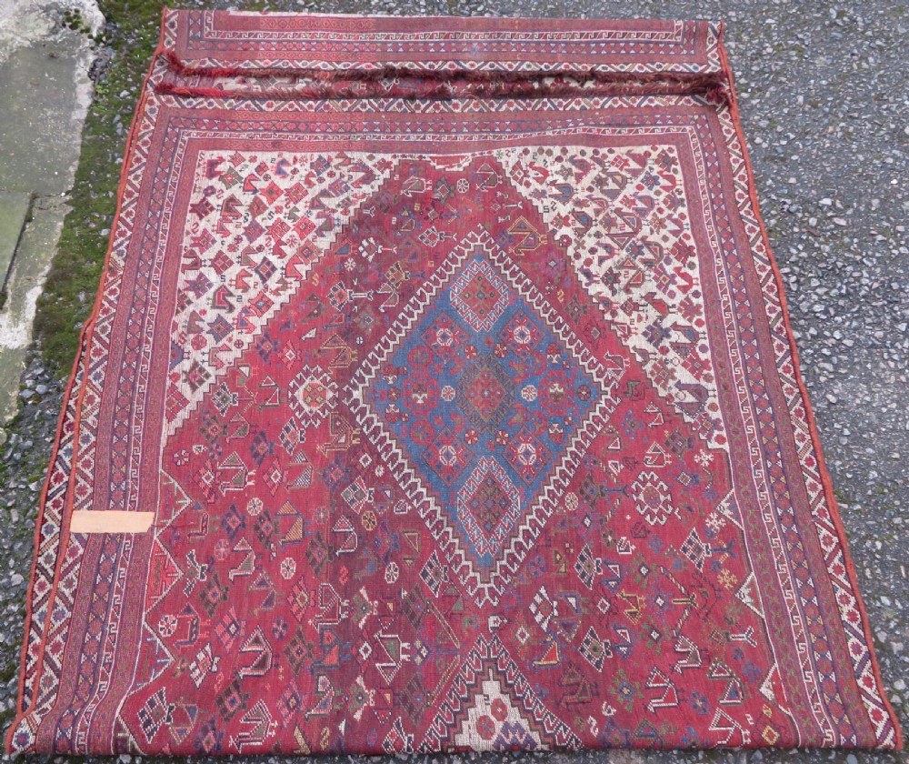 An antique hand-knotted Khamseh tribal kelleh carpet with a dark red field, geometric diamond medallions, and small bird motifs. View XXI