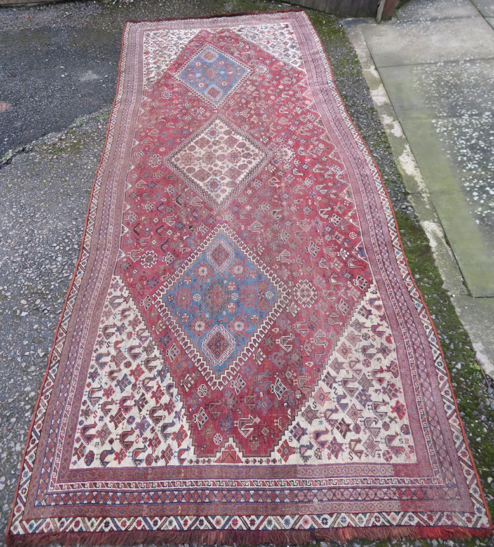 An antique hand-knotted Khamseh tribal kelleh carpet with a dark red field, geometric diamond medallions, and small bird motifs. View III