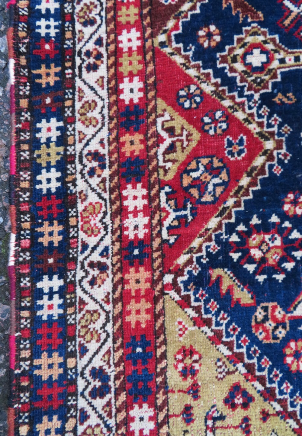 An antique hand-knotted Qashqai wool rug featuring a central ivory diamond medallion surrounded by detailed geometric and animal motifs on a navy blue field with a red border. View X